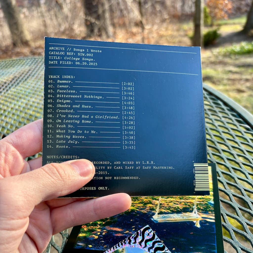Hand holding up the back cover of 'College Songs' CD with outdoor background.