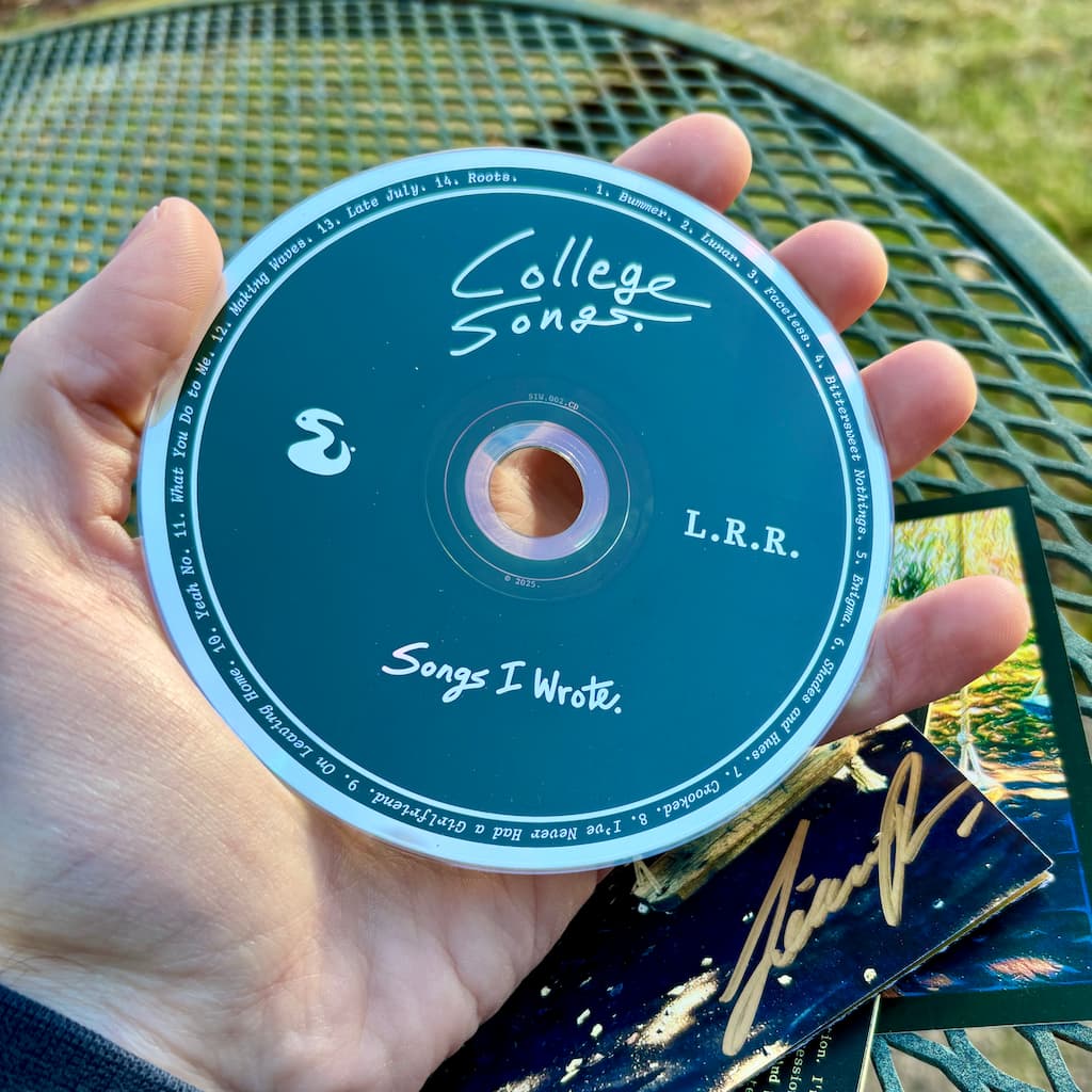 Hand holding a CD disc titled 'College Songs' with a scenic background.