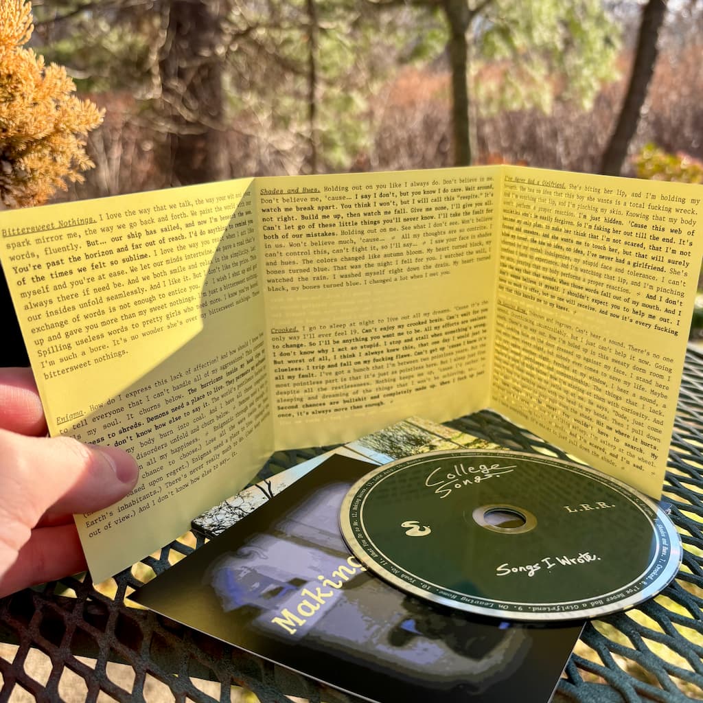 Music album with open yellow lyric inner sleeve and CD on a table outdoors.
