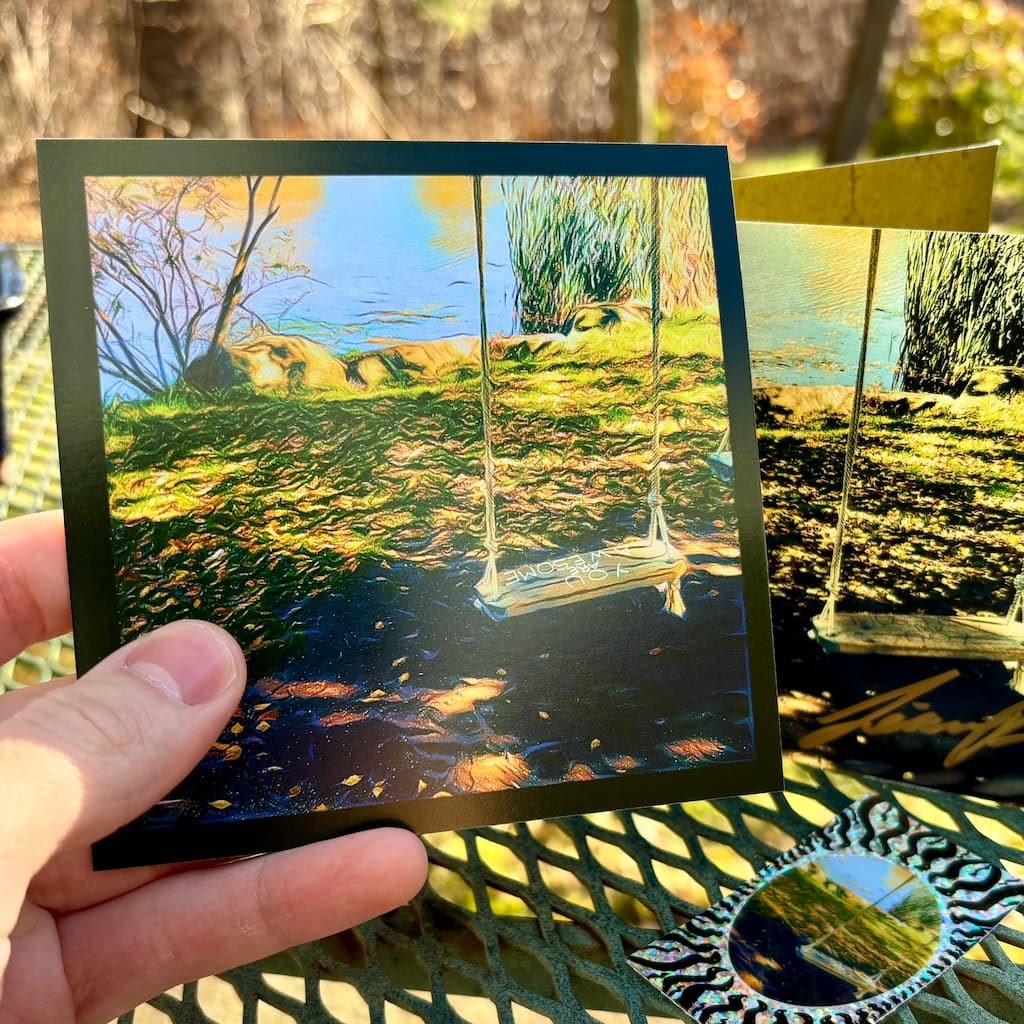Hand holding a small print of the special album art.