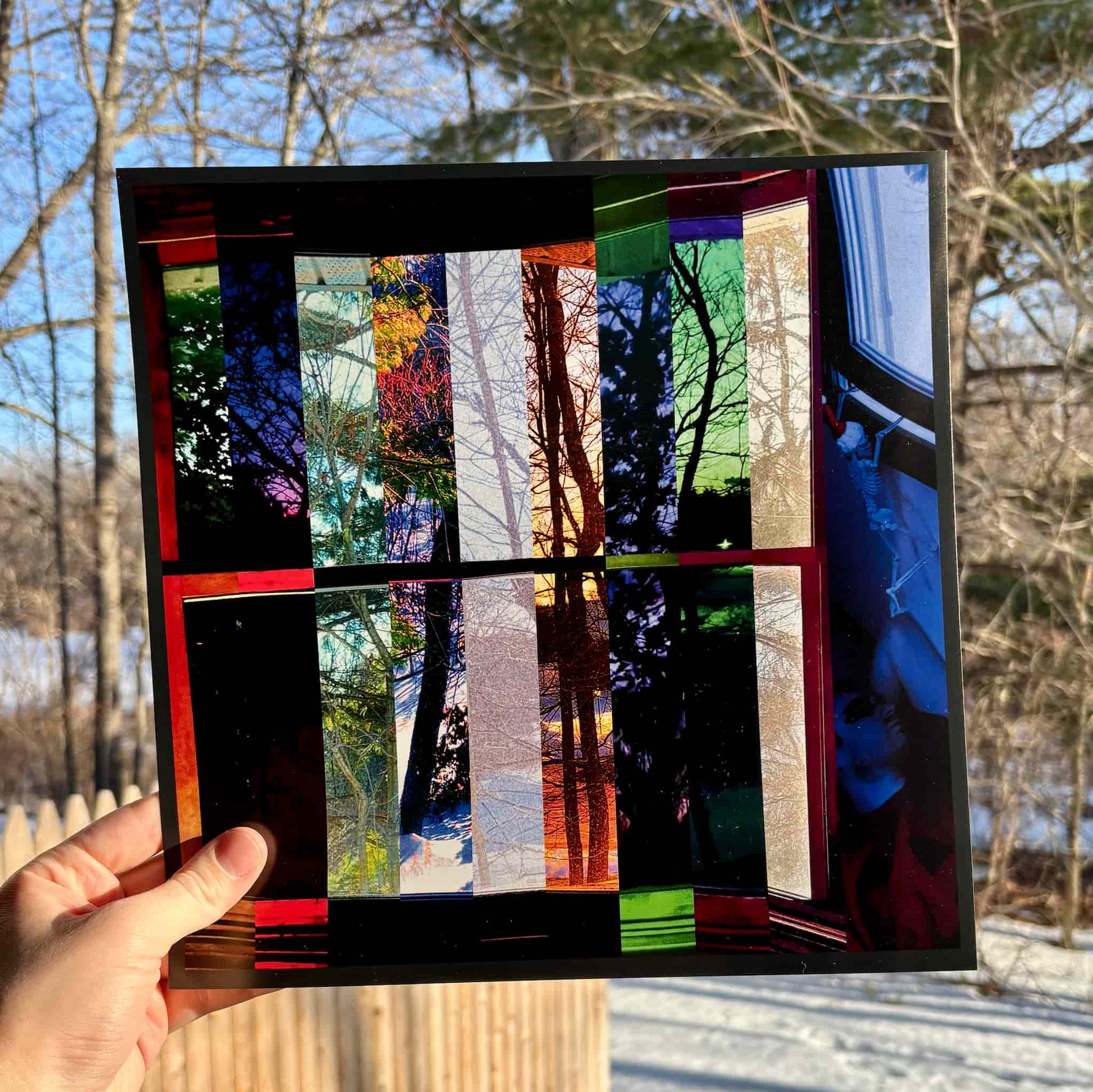 Colorful abstract art piece held by a hand with a natural background