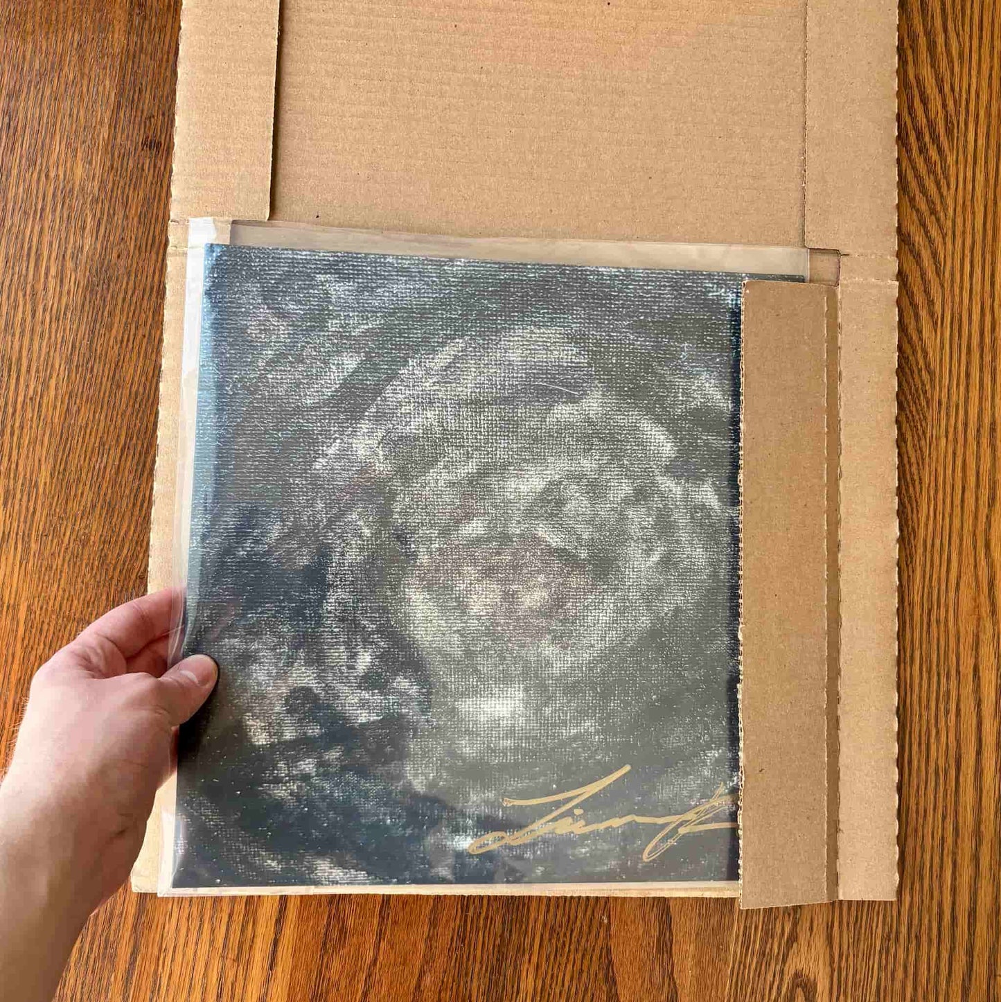 Person inserting signed vinyl record into shipping box
